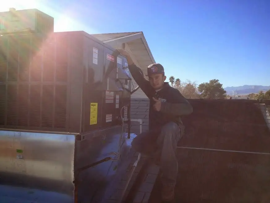 HVAC technician performing Heat Pump Repair on a rooftop unit in Sheridan