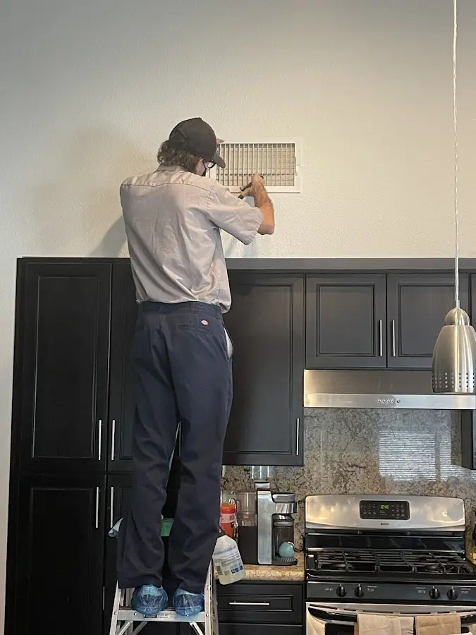 Technician inspecting an air vent during HVAC service in Sheridan